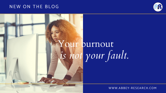 Image includes a picture of a young, Black woman standing at her desk, typing on a keyboard in front of a monitor. The text on the header includes "New on the blog" and the blog title "Your burnout is not your fault" and the web address www.abbey-research.com